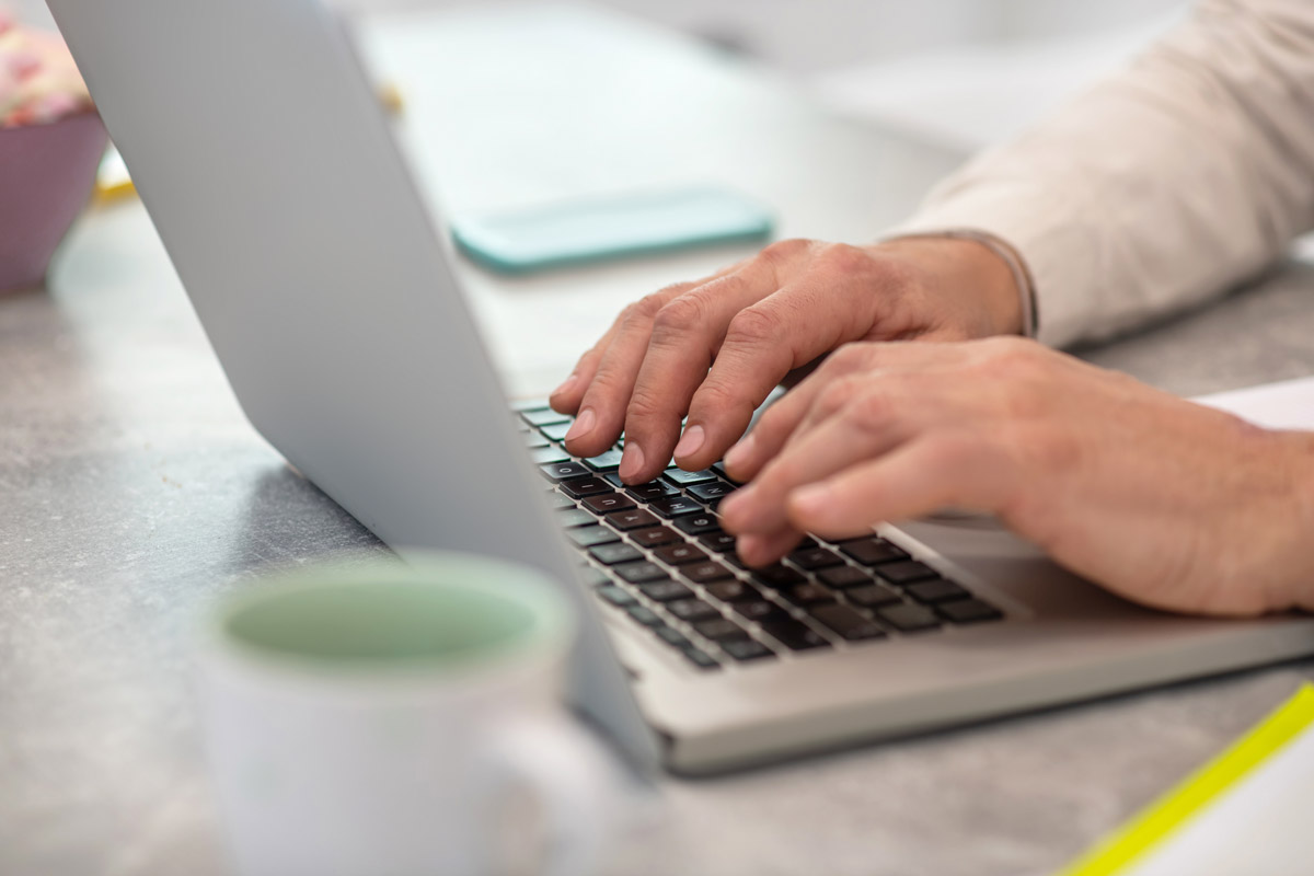 Typing a message. Close up picture of a man working on a laptop