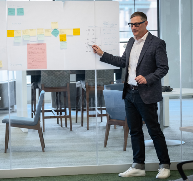 Brian Elms at a whiteboard teaching class