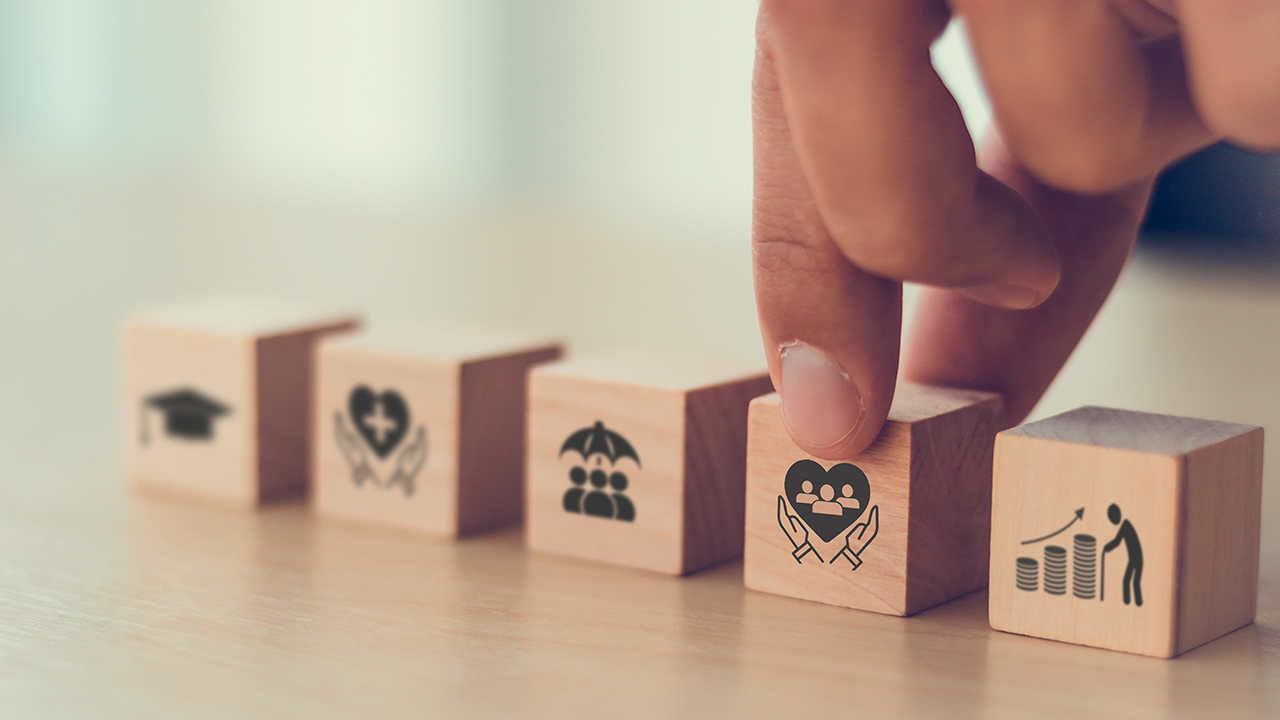 Fingers picking up a block with an image of hands holding up a heart.