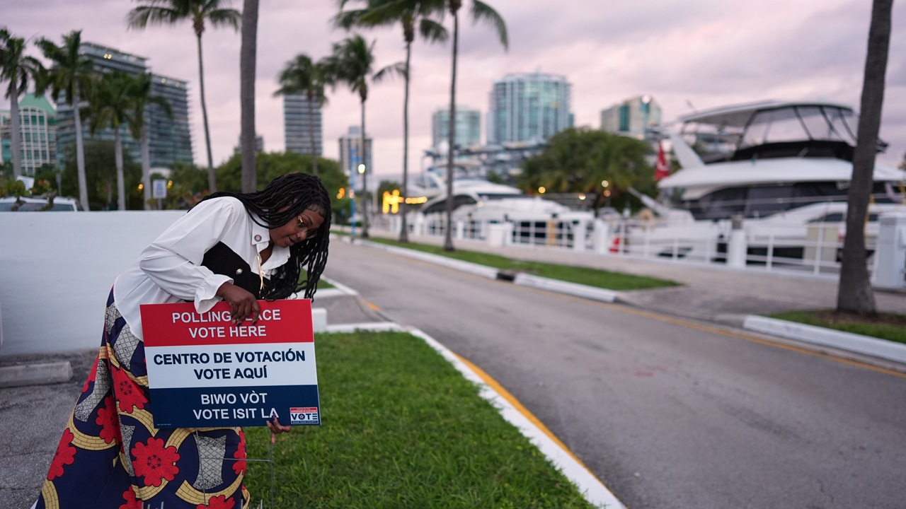 Photo of Polling place supervisor Bridget Knighton installs a sign