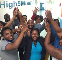 group of young black businessmen and businesswomen giving high fives in celebration