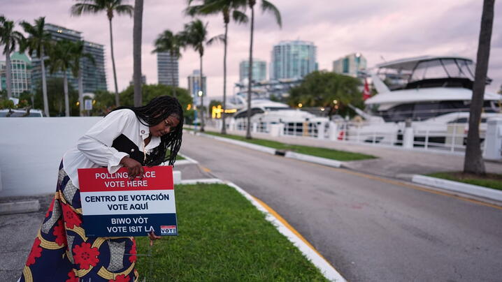 Photo of Polling place supervisor Bridget Knighton installs a sign