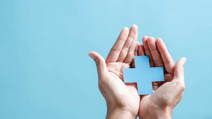 Image of hands holding a blue cross