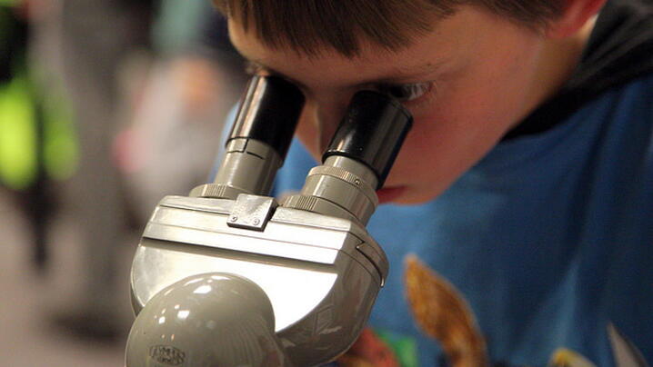 Child looking through a microscope image of a child looking through a microscope