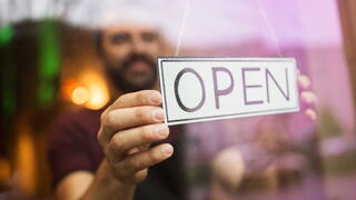 Image of person turning around an "Open" sign on a business