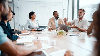 Stock photo of people sitting around conference table