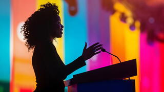 Silhouette of a woman presenting at a podium